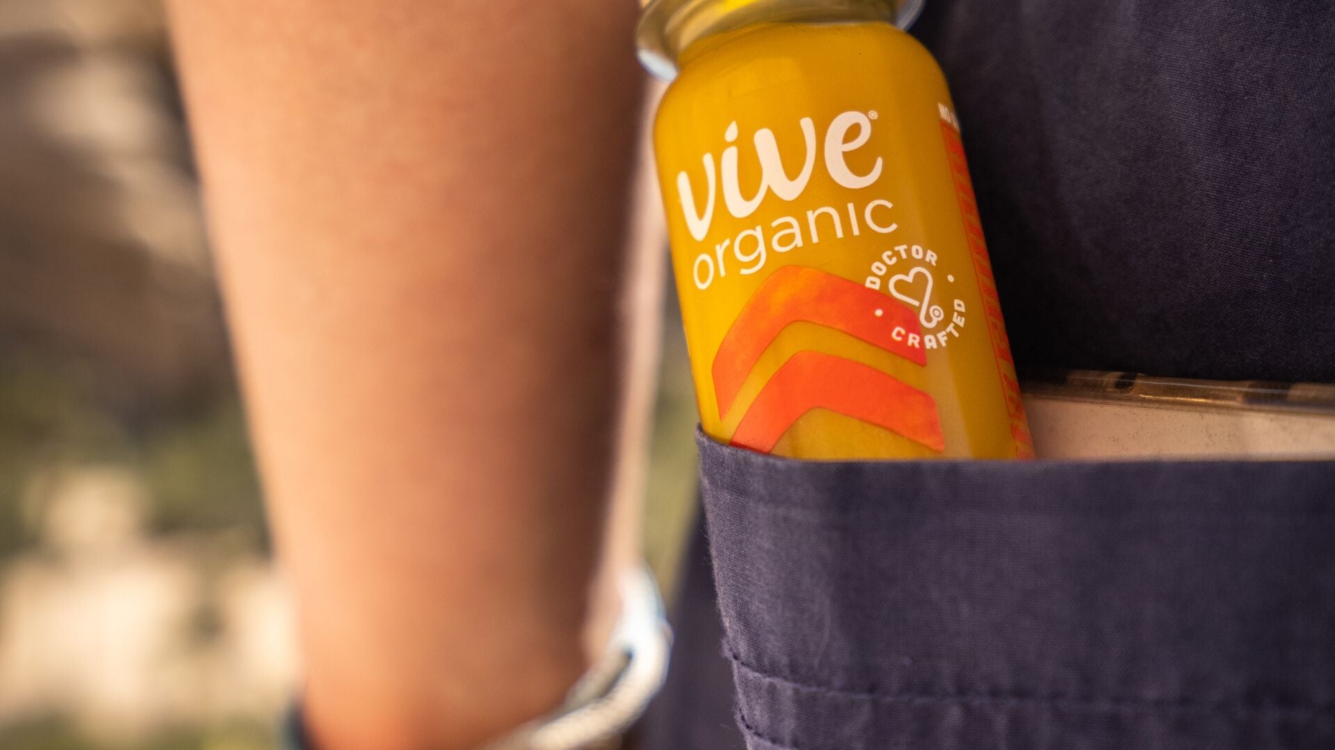 A Vive Organic wellness shot tucked into a shorts pocket, ready to grab on the go
