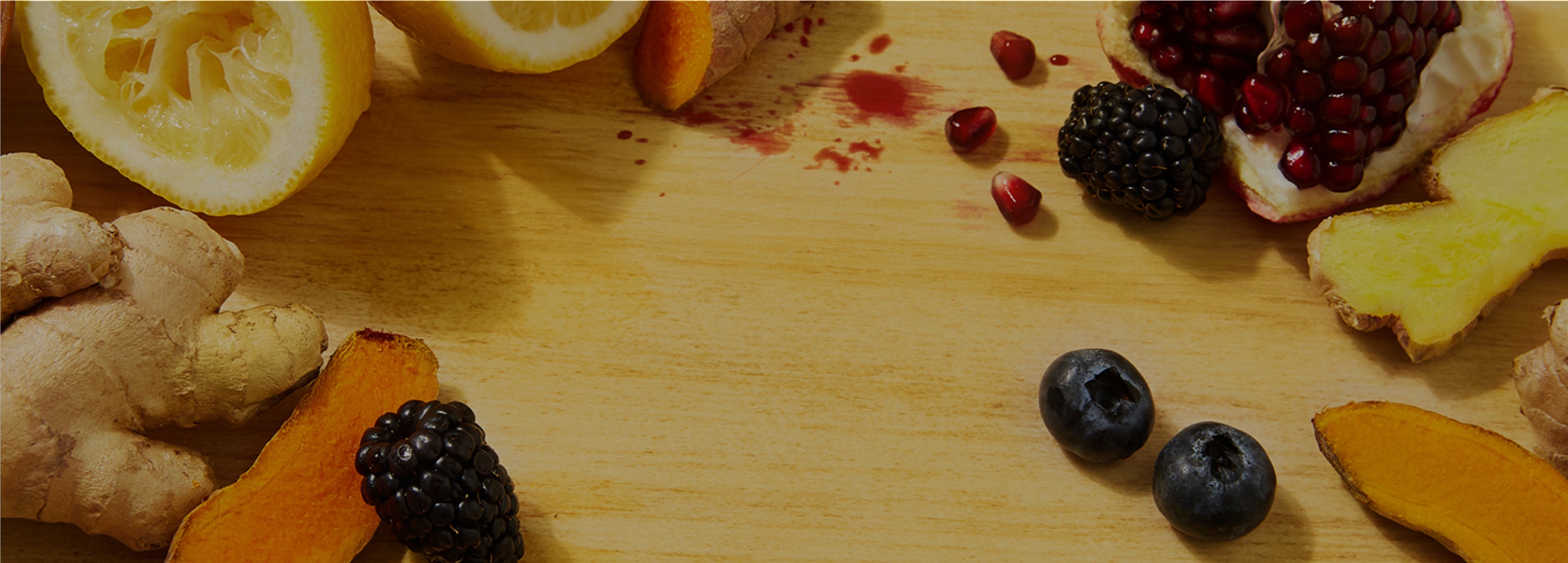 fresh lemon, blueberries, pomegranate, ginger, turmeric ingredients on a chopping board