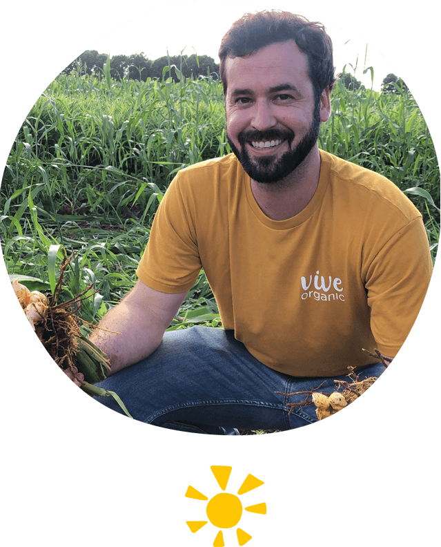 one of the founders of vive organic, Kyle, and other male team members sitting on the ground in a turmeric farm field