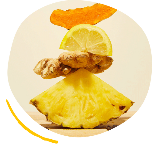 Turmeric root, lemon, ginger, and slice of pineapple stacked on top of each other